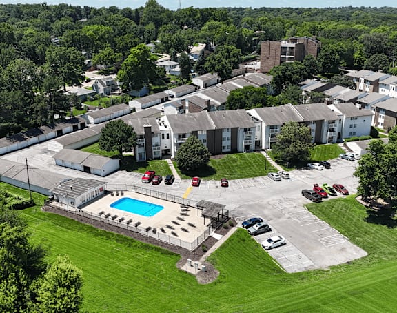 A parking lot in front of a building surrounded by trees.