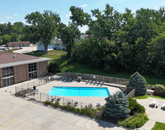 A parking lot in front of a building surrounded by trees.