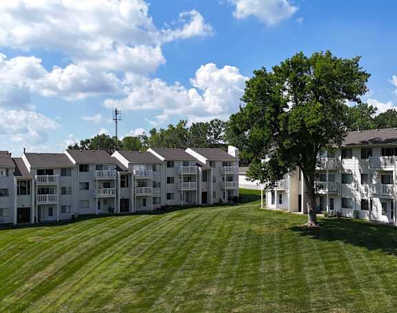 A parking lot in front of a building surrounded by trees.