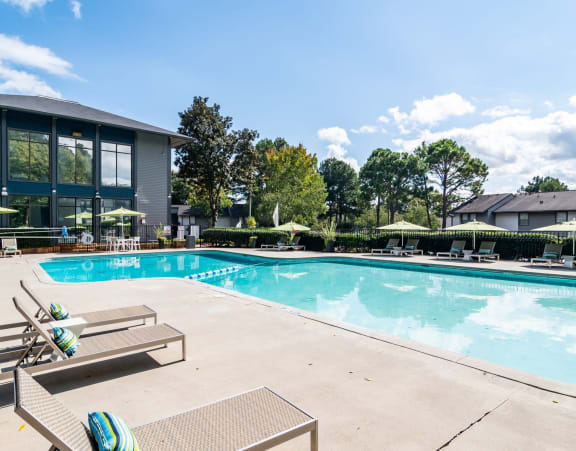 a swimming pool with chairs and umbrellas next to a building at Glen Hollow, Decatur, GA