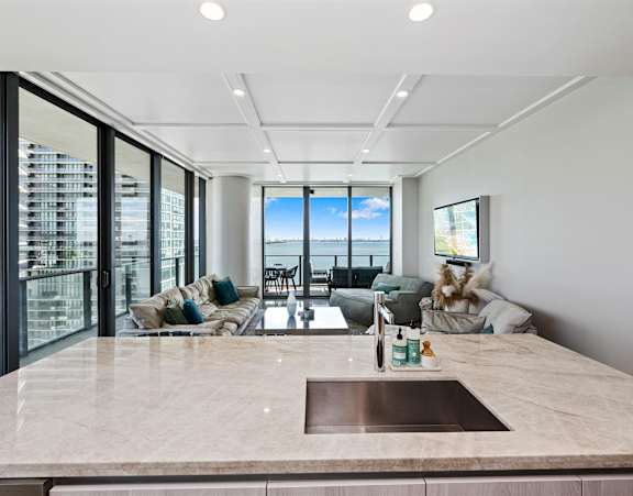 A modern living room with a glass table and white chairs.