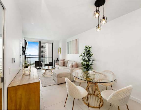 A modern living room with a glass table and white chairs.