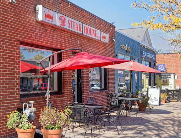 A red umbrella is on the patio of a Steak House.