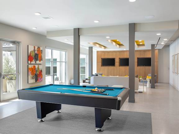 A pool table in a room with a wooden cabinet and a painting on the wall.