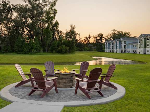 A fire pit surrounded by chairs in a backyard.