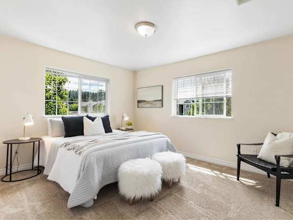 A bedroom with a large bed, a bench, and a window.