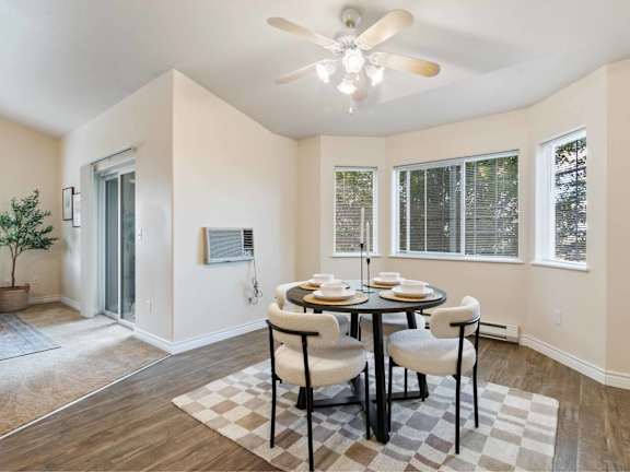 A dining room with a table set for two and a ceiling fan.