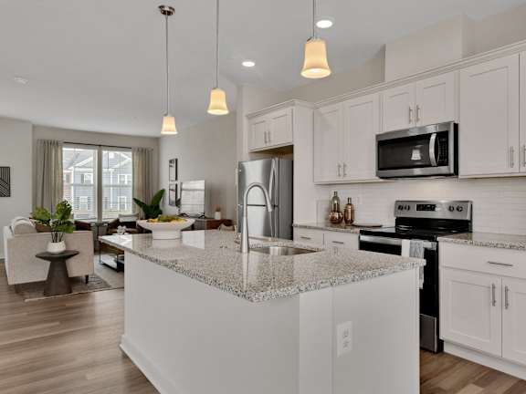 an open kitchen and living room with white cabinets and granite counter tops