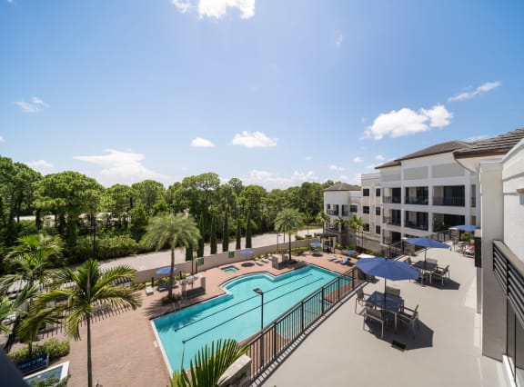 a swimming pool with tables and umbrellas in front of a building