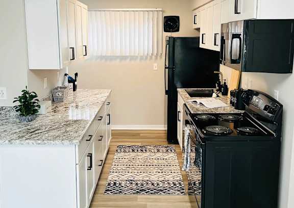 A kitchen with black appliances and white cabinets at Eton Square Apartments and Townhomes, Michigan, 48009