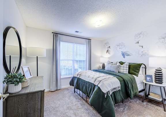 A bedroom with a bed, a dresser, and a mirror.