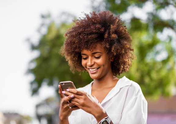 Woman smiling at her phone at Cordova Creek Apartments, Cordova, Tennessee