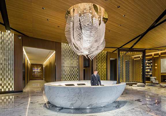 a man stands in the lobby of a hotel with a large circular desk and a