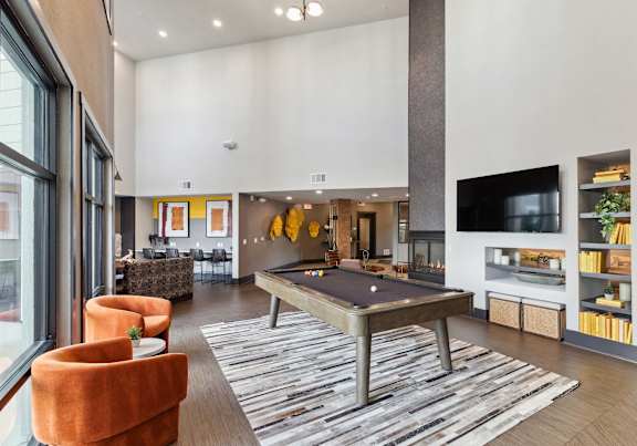 A living room with a pool table and a television.