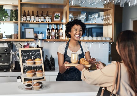 a woman handing a tray of donuts to a customer in a bakery  at Briarcliff Apartments in North Druid Hills, 30329