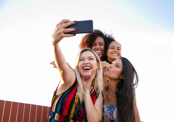 a group of women taking a picture with a cell phone