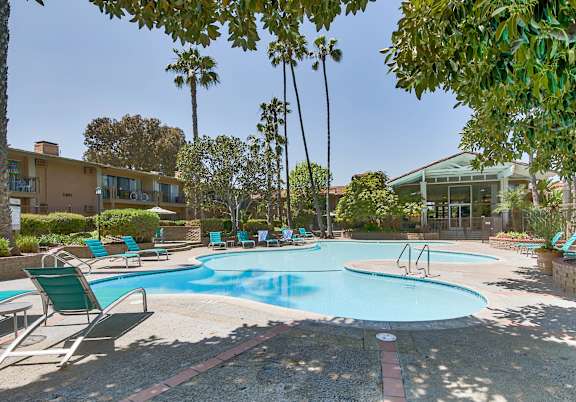 a swimming pool with chairs and trees around it