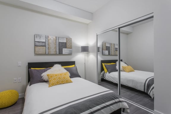 two beds with yellow pillows in a room with mirrors