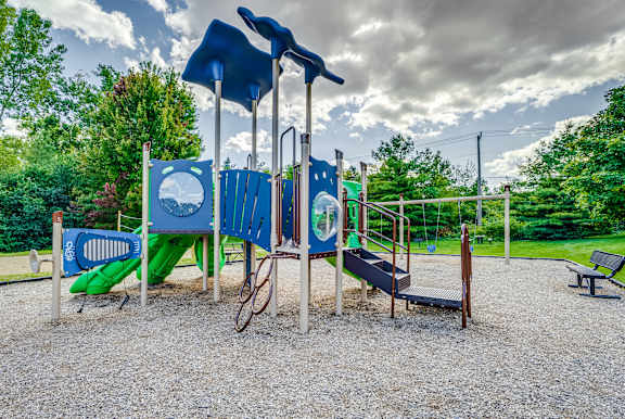 A playground with a blue slide, a green slide, and a wooden swing set.
