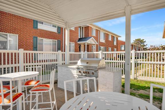 A patio with a grill and chairs is set up.