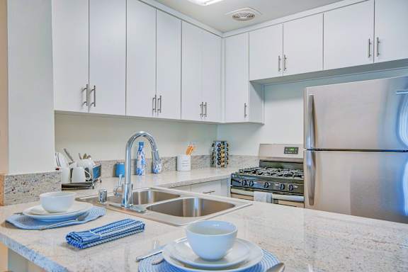 A kitchen with a stainless steel refrigerator and a granite countertop.