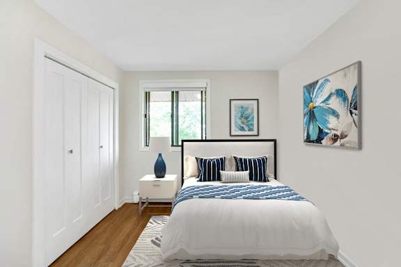 A bedroom with a bed, nightstand, and two framed pictures on the wall.