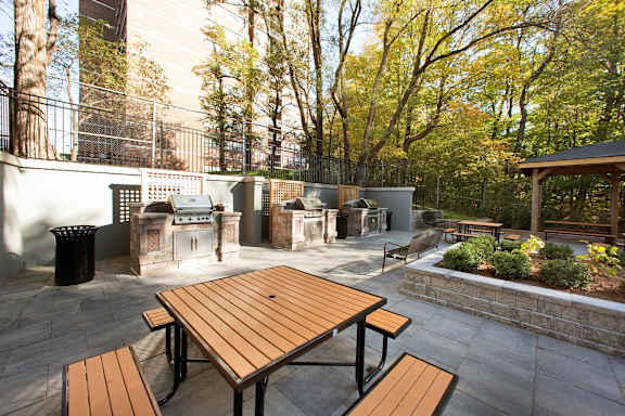 a patio with a picnic table and barbecue grill