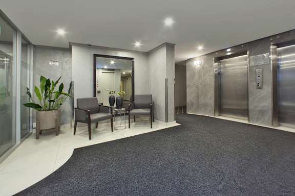 a lobby with chairs and a table in front of elevators