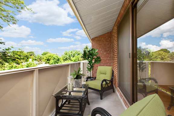 A balcony with a table and chairs overlooking a green landscape.