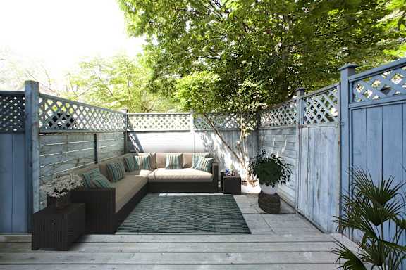 a patio with a couch and a rug on a wooden deck