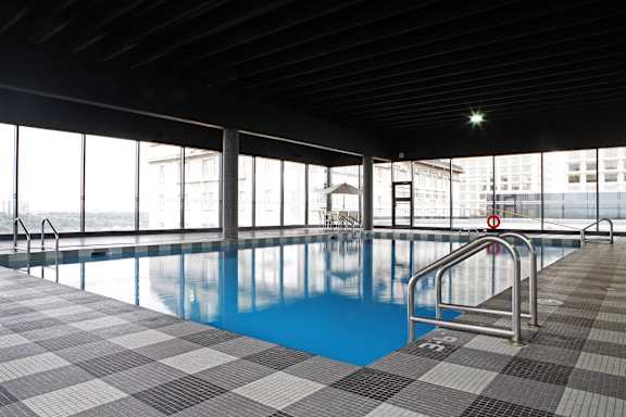 a swimming pool in a high rise building with glass walls and a blue water