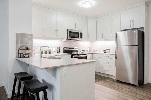 a kitchen with a large island and stainless steel refrigerator