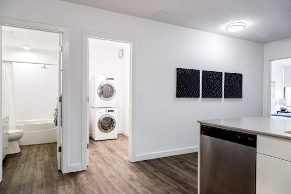 an open kitchen and laundry room with a washer and dryer and a bathroom