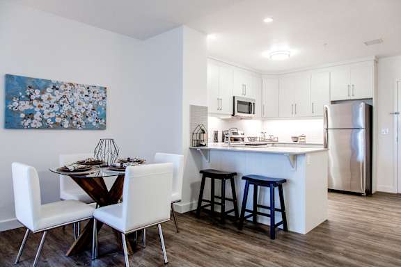 a kitchen and dining area with white cabinets and a stainless steel refrigerator