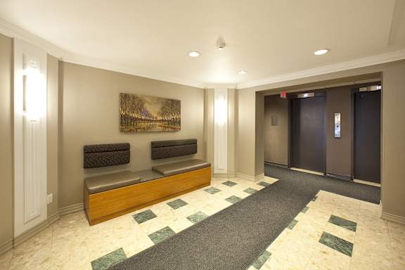 a lobby with two benches and two elevators and a painting on the wall