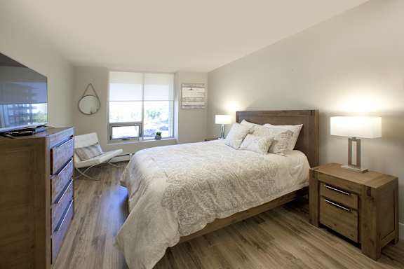 A bedroom with a bed, nightstand, and window.
