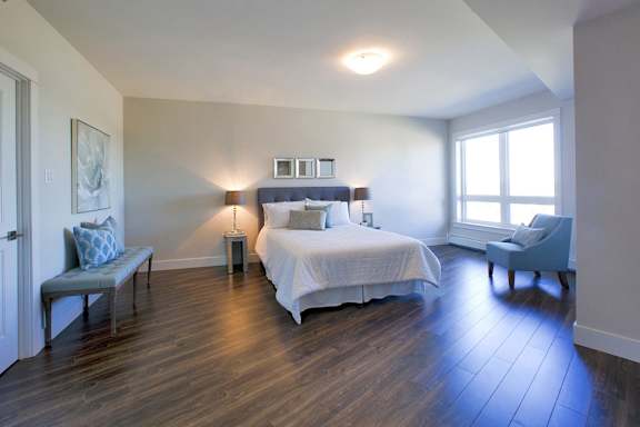 A bedroom with a bed, nightstand, and chair.