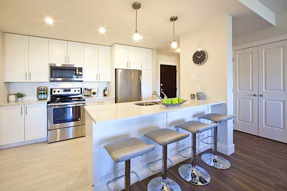 A kitchen with a white counter and bar stools.