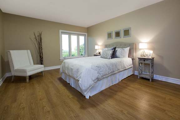 A bedroom with a large bed and a chair.
