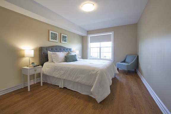 A bedroom with a bed, nightstand, and chair.