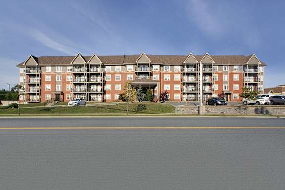 A large red brick apartment building with a parking lot in front.