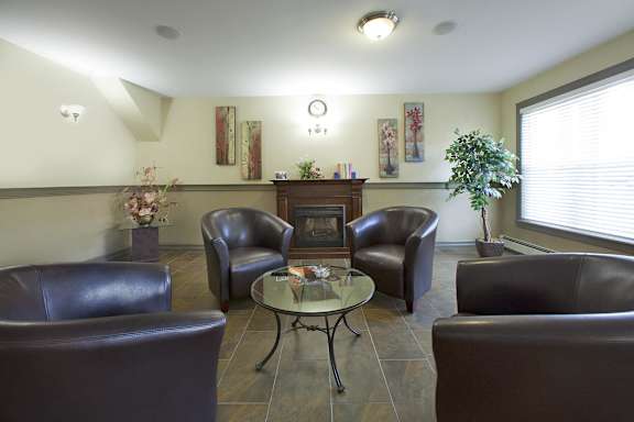 A living room with brown leather chairs and a glass table.