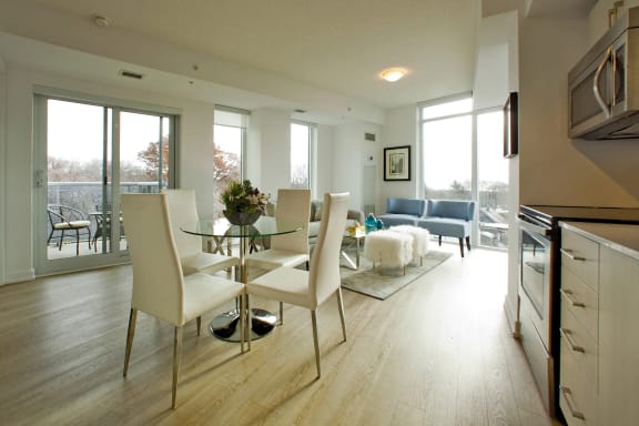 a dining room and living room with a glass table and white chairs