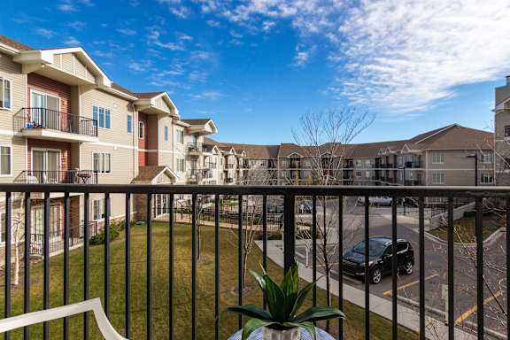 the view from the balcony of an apartment complex with a car parked on the street