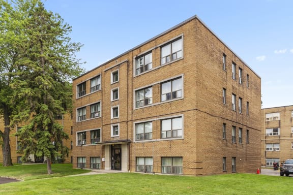a brick building with a green lawn and a tree