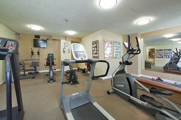 a gym with various exercise equipment and a tv