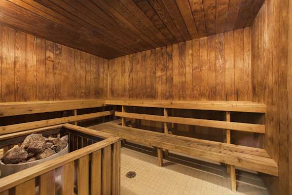 a sauna with wooden benches and a bucket of rocks
