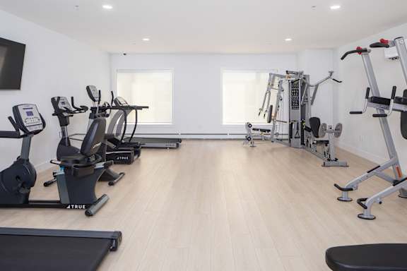 A gym with a variety of equipment including treadmills, stationary bikes, and weight machines.