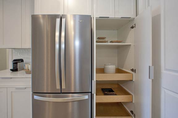 A stainless steel refrigerator with its door open and a shelf with a bowl and a book on it.