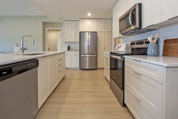 A modern kitchen with white cabinets and stainless steel appliances.